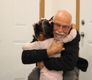 Josiah's daughter gives a Habitat supporter a hug at the end of their home dedication.