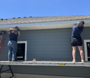Volunteers add soffit and facia to the twin home that is furthest along in the building process.