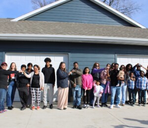 Four families smile with their keys alongside the Habitat supporters who made it possible.